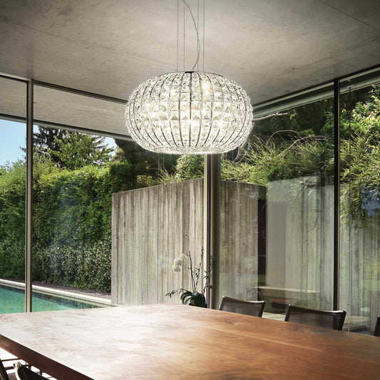 Modern dining room with Ideal Lux CALYPSO pendant light, featuring sparkling crystals and adjustable height, hanging above a wooden table.