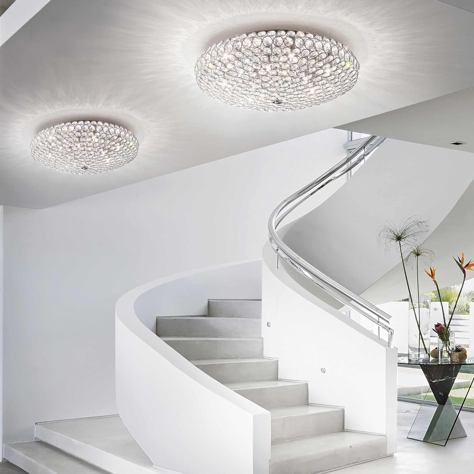 Modern staircase with IDEAL Lux King 9-light gold ceiling fixture featuring sparkling crystals, enhancing elegance in a contemporary space.