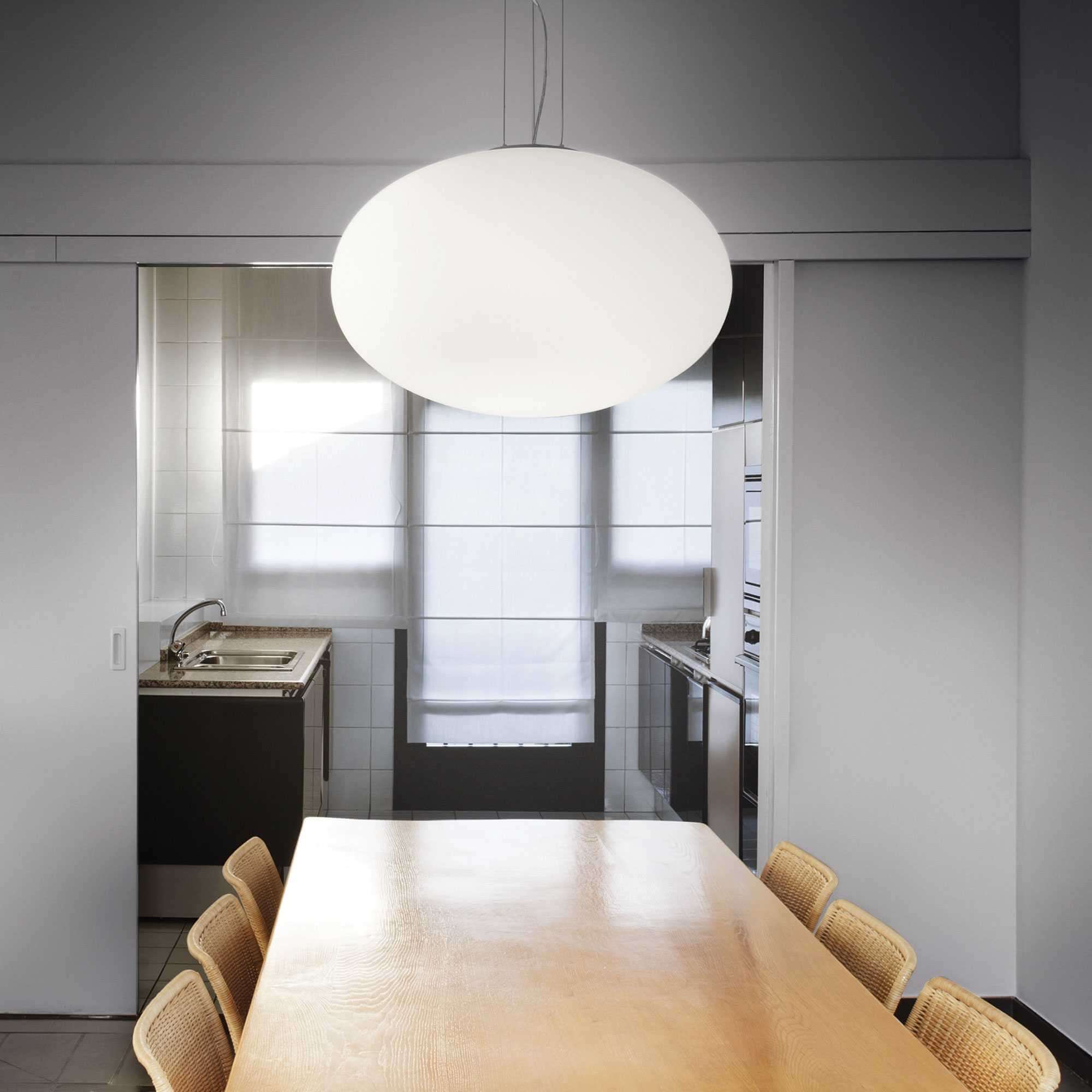 Ideallux Pendelleuchte CANDY 50cm in modern dining room, adjustable height with white glass diffuser, over wooden table.