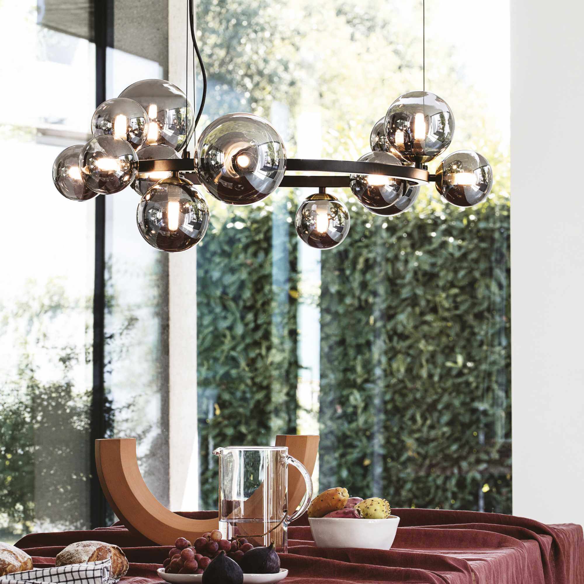 Modern dining room with Ideal Lux Pendelleuchte PERLAGE chandelier featuring 14 glass globes and metallic finish, hanging over a table.
