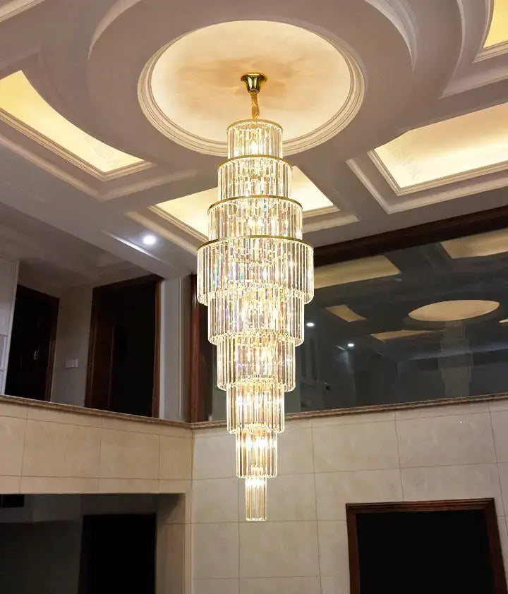 Luxurious crystal chandelier with spiral design hanging in a hotel's grand staircase, featuring adjustable height and dimmable lights.