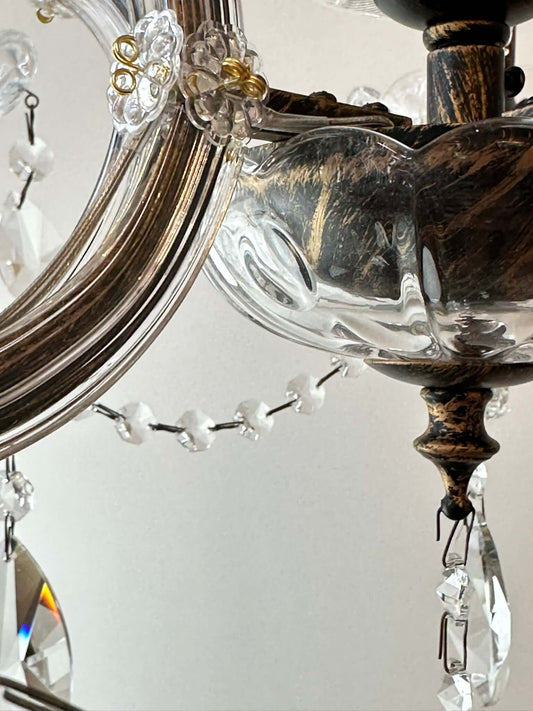 Close-up of antique-style crystal chandelier with ornate glass and metal design, featuring sparkling crystal accents.