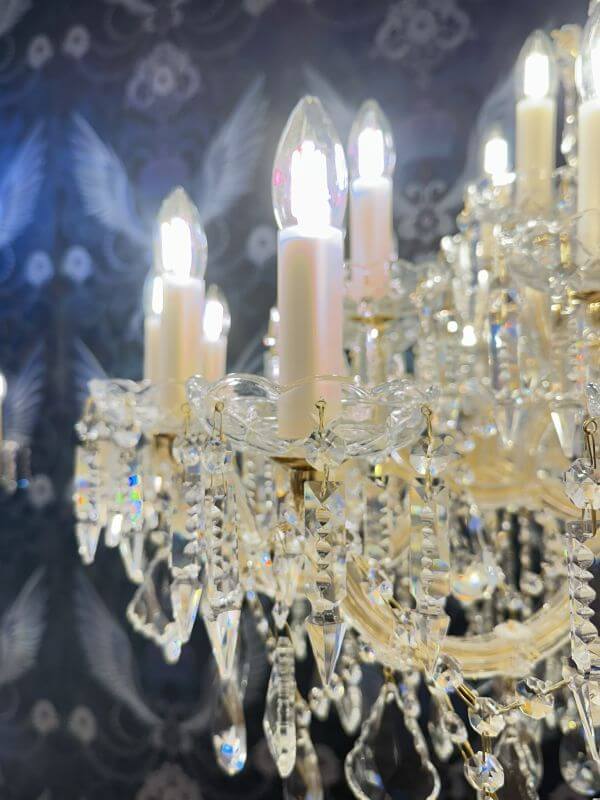 Close-up of luxury gold chandelier with crystal arms and 36 lights, showing detail of glowing LED bulbs and sparkling crystals.