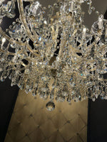 Luxurious gold chandelier with crystal arms and intricate glass detailing, showcasing elegance and brilliance.