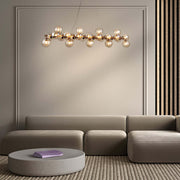 Modern living room featuring a Maytoni Pendelleuchte DALLAS chandelier with amber glass globes and metallic finish over a neutral sofa.