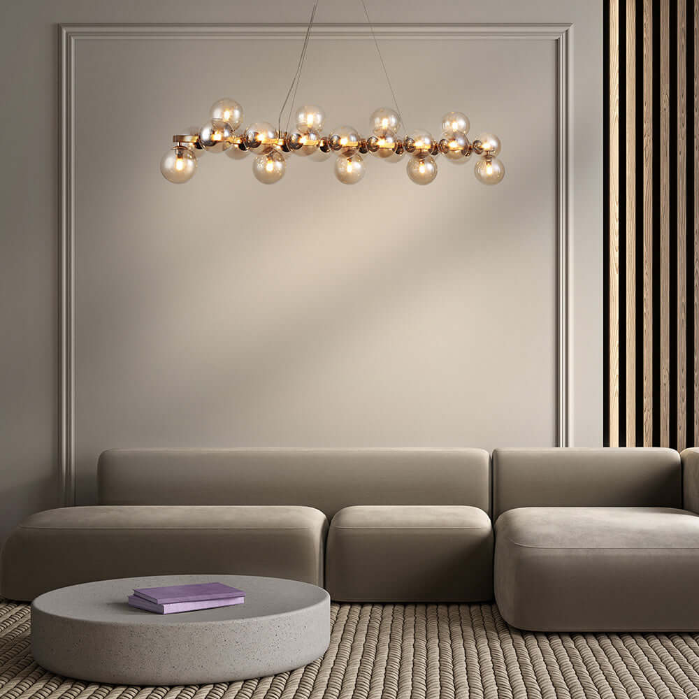Modern living room featuring a Maytoni Pendelleuchte DALLAS chandelier with amber glass globes and metallic finish over a neutral sofa.