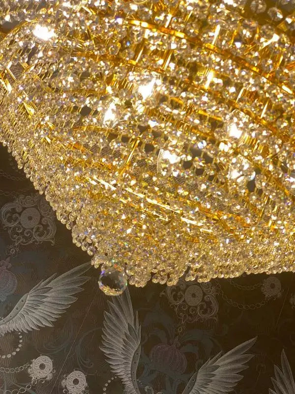 Gold crystal ceiling light Granada, Ø60cm, close-up, showcasing radiant cut crystals, set against a patterned backdrop.