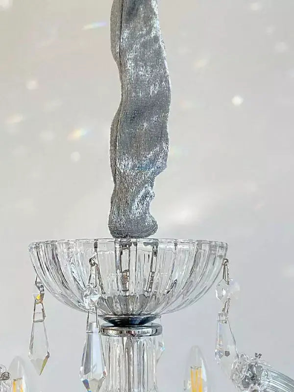 Close-up of Kristall Kronleuchter SERENADE with crystal glass arms and chrome accents, showcasing intricate crystal details.