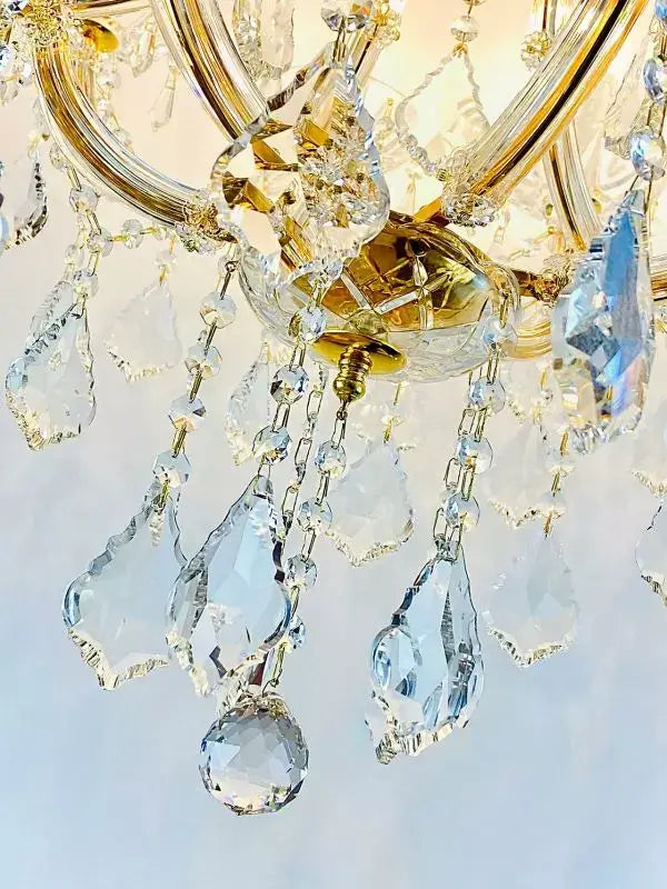 Close-up of sparkling crystal glass details on a gold-plated chandelier arm, emphasizing the luxurious design and craftsmanship.