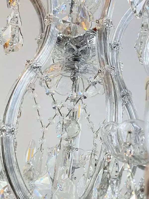 Detail of exclusive crystal chandelier with glass-encased arms, showcasing intricate design and shimmering crystals.