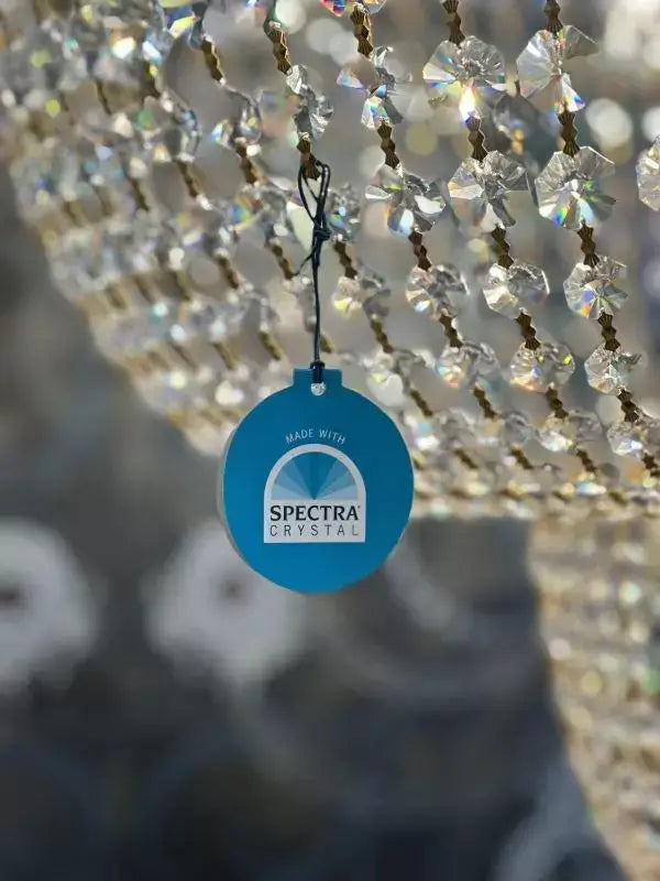 Close-up of Swarovski Spectra crystals on a gold chandelier with a blue "Made with Spectra Crystal" tag