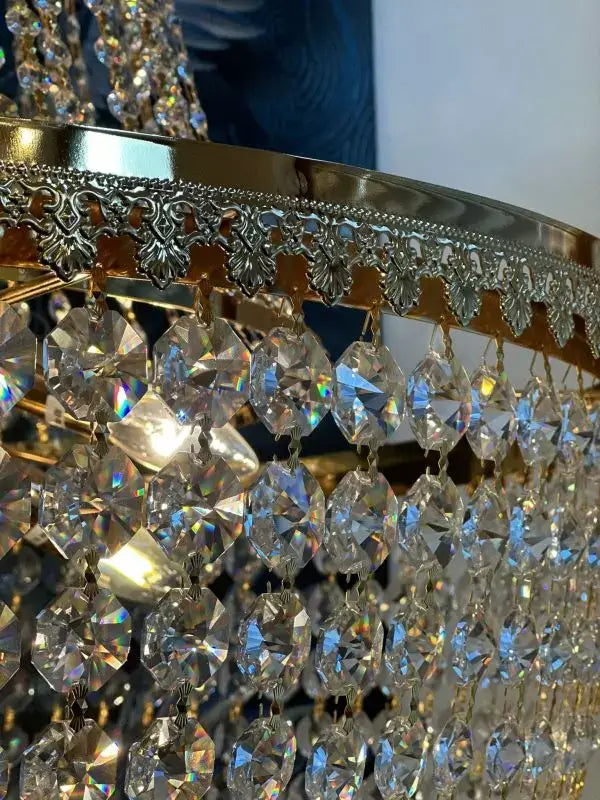 Gold-finished chandelier with Swarovski Spectra crystals, featuring intricate detailing and sparkling crystal prisms.