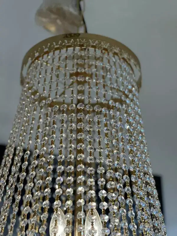 Gold-colored Swarovski crystal chandelier with Spectra details, featuring an intricate design and a shimmering finish.