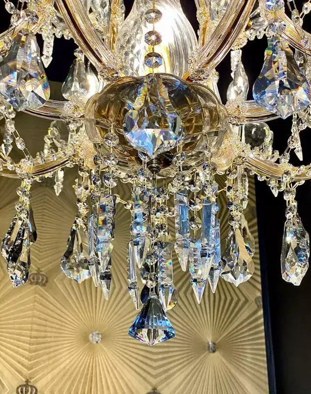 Close-up of exclusive crystal chandelier with gold accents and crystal glass arms, showcasing intricate hanging crystals.