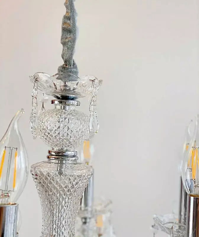 Close-up of a crystal chandelier with intricate details and LED bulbs, featuring sparkling cut crystal and chrome accents.