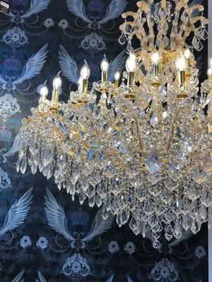 Gold Maria Theresia chandelier with crystal arms and 42 lights, shown in lavish setting, highlighting intricate design and brilliance.
