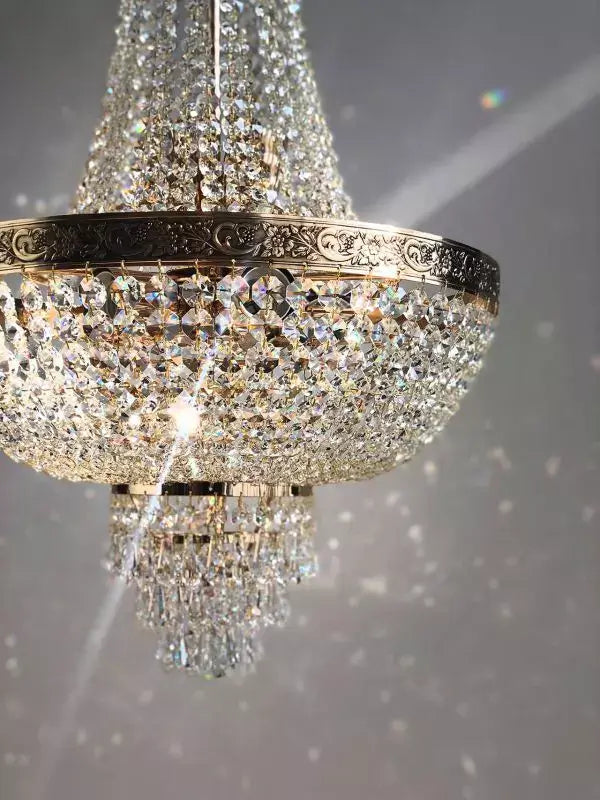 Luxurious Kristall Korblüster Plaza Gold chandelier with cut crystals and gold finish, sparkling elegantly in natural light.
