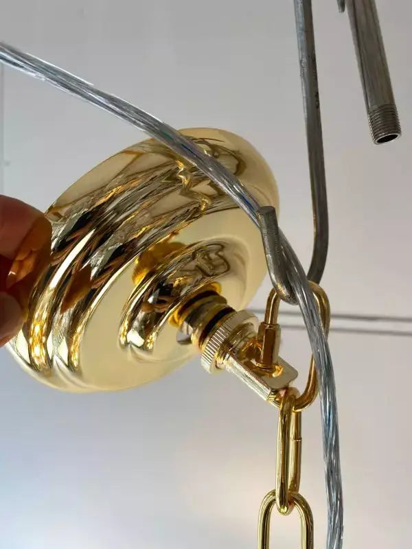 Close-up of gold hanging fixture assembly for KRISTALL RIVA pendant light with adjustable chain and wiring.