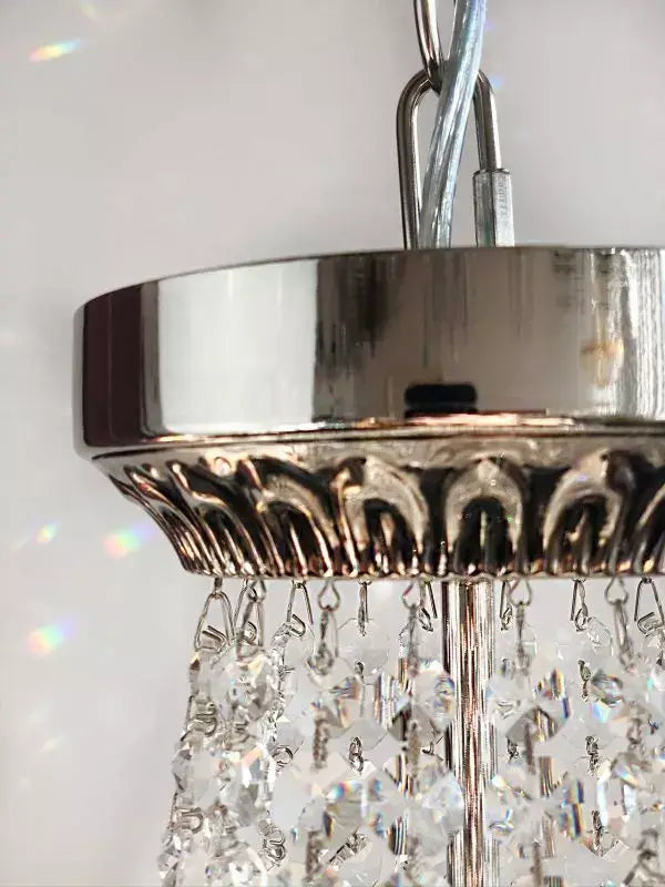 Close-up of a silver crystal chandelier with intricate metal design and sparkling cut crystals, ideal for elegant room decor.