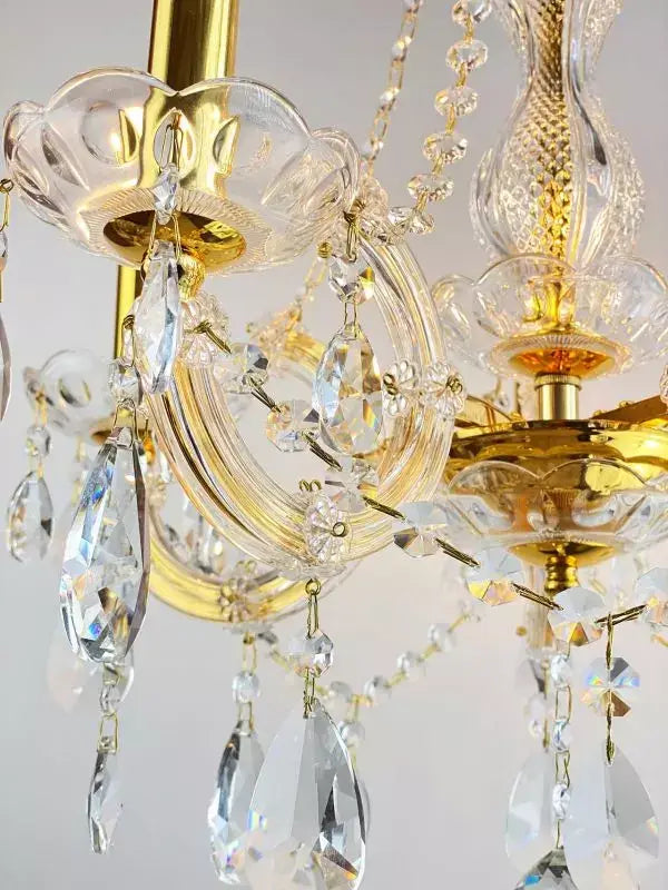 Luxurious gold and crystal chandelier with sparkling lead crystals, featuring intricate brass and glass detailing.