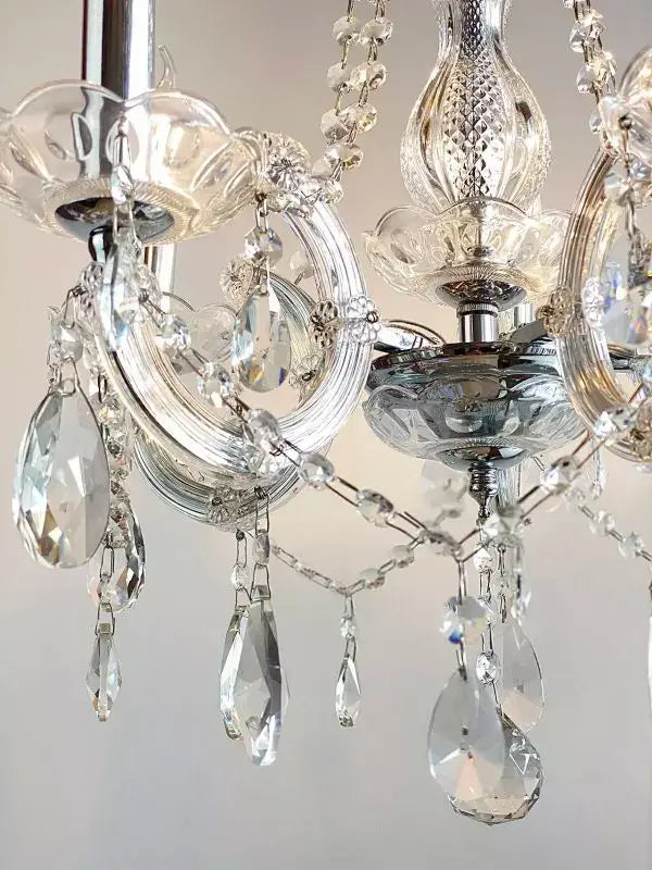 Close-up of Kristall Kronleuchter with sparkling lead crystals and chrome elements, featuring intricate glass arms and chain details.