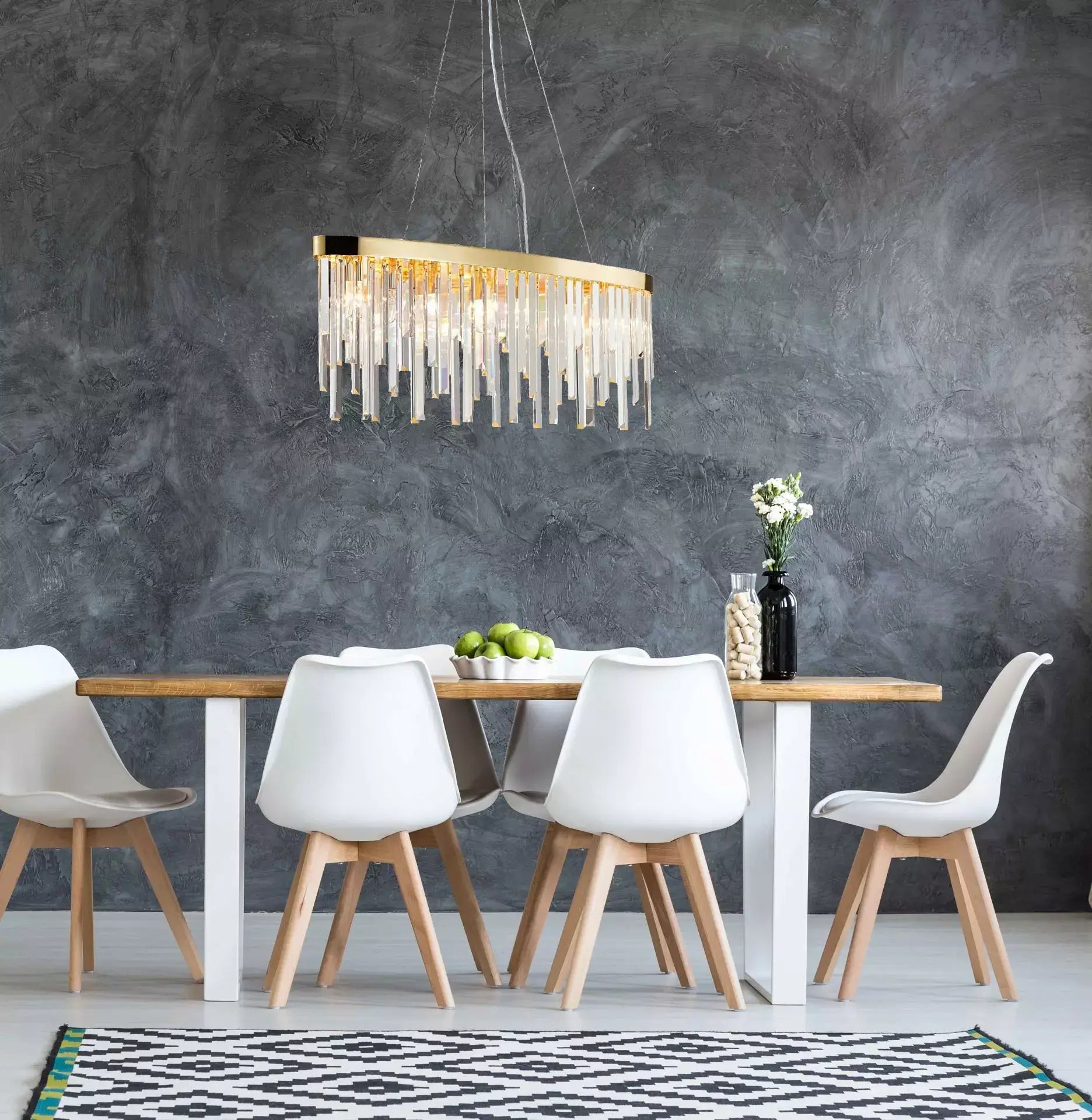 Luxury Starnberg 90cm gold chandelier with sparkling crystal rods hanging above a modern dining table with white chairs.